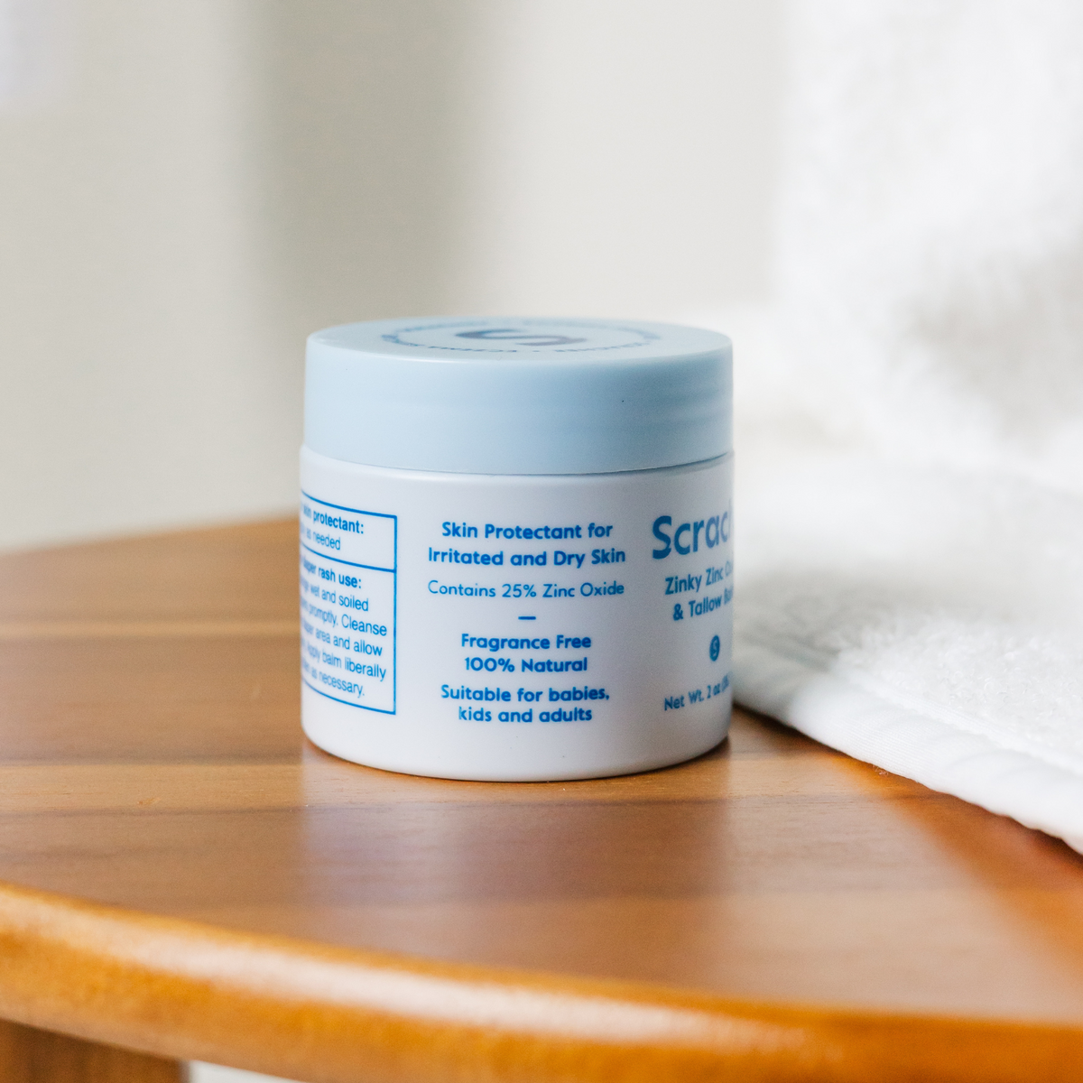 Jar of Scrachee skin protectant balm on a wooden surface with a white background