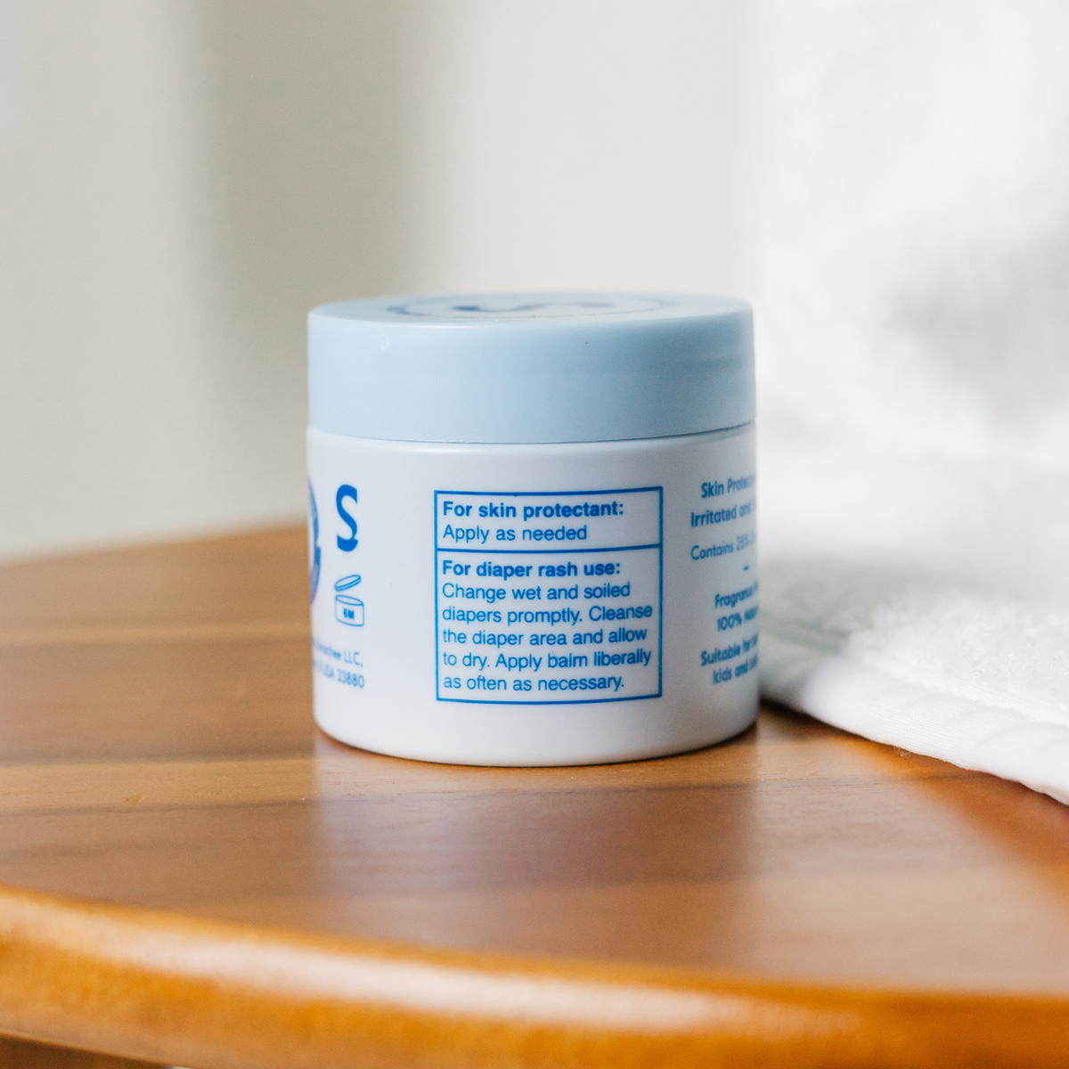 Jar of Scrachee skin protectant balm with blue lid on a wooden surface