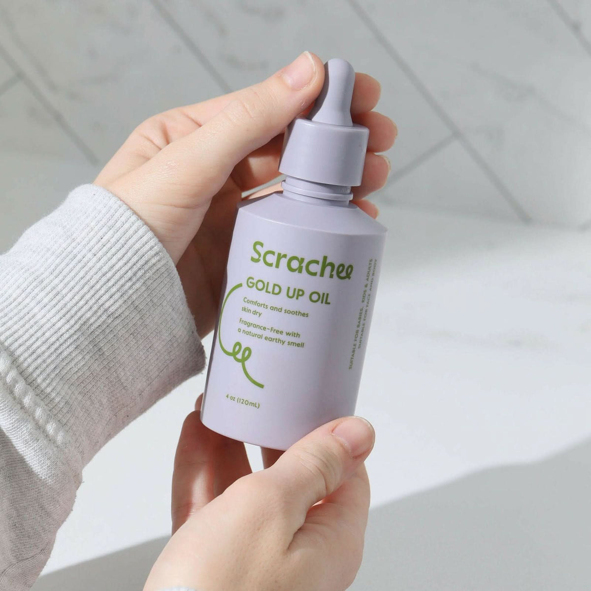 Someone holding Scrachee's Gold Up Oil in her hands.