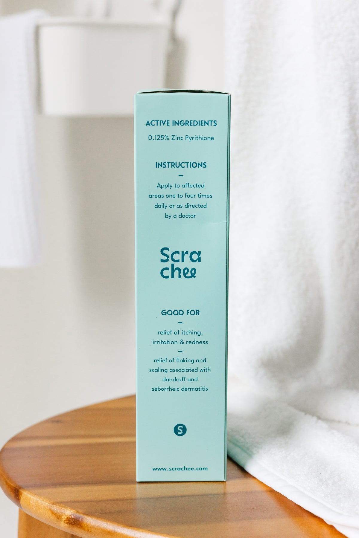 Scrachee product box on a wooden surface with a white towel in the background