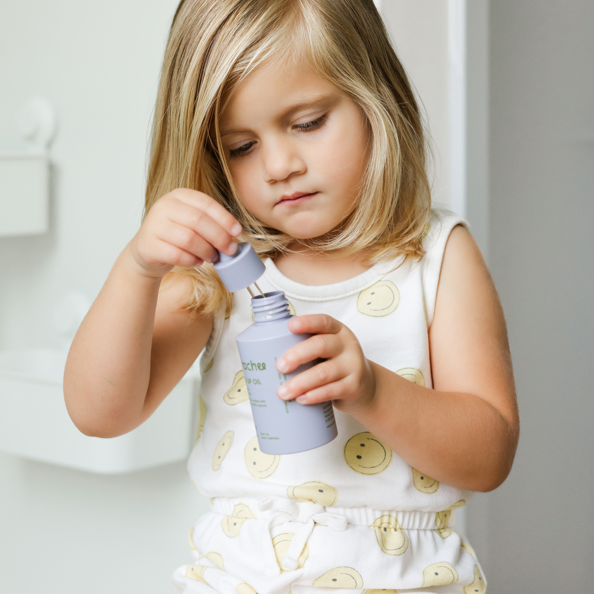 Young girl holding a purple bottle with a neutral background
